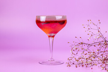 Summer cocktail and little flowers on pink background. Refreshing summer drink abstract concept.