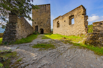 Fototapeta na wymiar Ruins of the castle of Esch-sur-Sure with a broken stone fence, wall with square windows and a square tower in the background, green grass, sunny summer day with a blue sky in Luxembourg