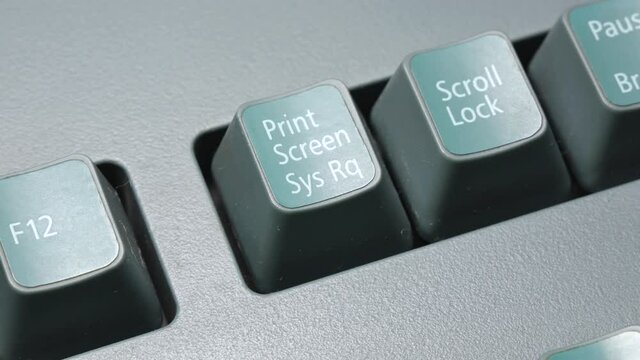 Man pressing the print screen key, finger pushing the screenshot button Sys Rq key on a desktop pc keyboard. Macro, extreme closeup. Screen capping, screenshotting, doing a print screen simple concept