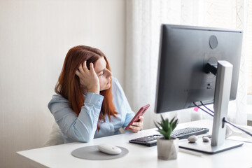 Tired woman stressed by a lot of work, sitting at the desk and using smartphone on social distance