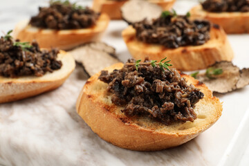 Delicious bruschettas with truffle sauce and thyme on white table, closeup