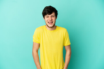 Young Russian man isolated on blue background laughing