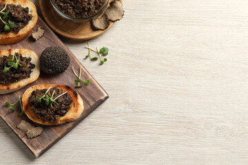 Delicious bruschettas with truffle sauce and microgreens on white wooden table, flat lay. Space for text