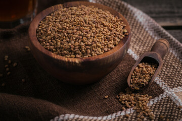 Bowl of fenugreek dry seeds on dark wooden background. Healthy food, Ayurveda and alternative medicine concept