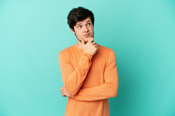 Young Russian man isolated on blue background thinking an idea while looking up