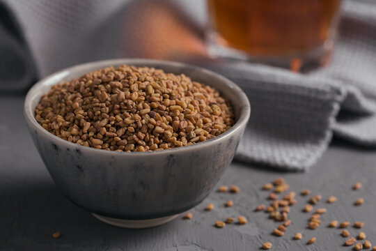 Bowl of fenugreek dry seeds on grey background. Healthy food, Ayurveda and alternative medicine concept