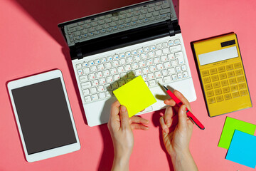 Women's hands with items for business on a bright, colored background. 