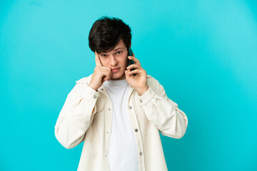 Young Russian man using mobile phone isolated on blue background thinking an idea