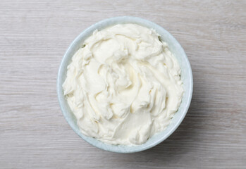 Bowl of tasty cream cheese on white wooden table, top view