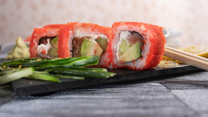 three pieces of roll with caviar, lemon, sticks, cucumber