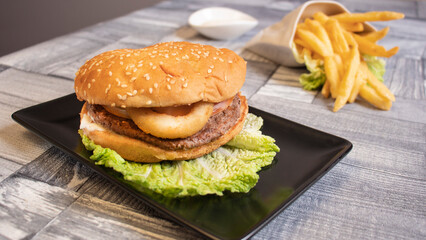 hamburger on a black plate and golden fried potatoes