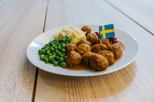  woman eating Swedish traditional meatballs with fried potatoes and cranberry sauce. Swedish food concept.