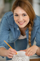 happy young teacher painting a self-made earthenware at lesson