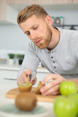 Fototapeta premium man cutting a kiwi fruit in half