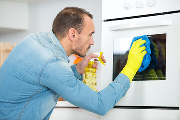 man cleaning oven in domestic kitchen
