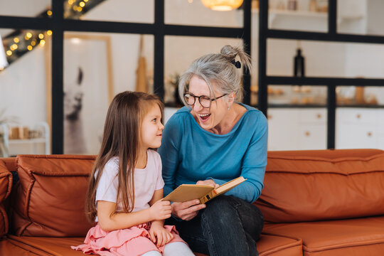 Nice elderly woman grandmother reading story to granddaughter.