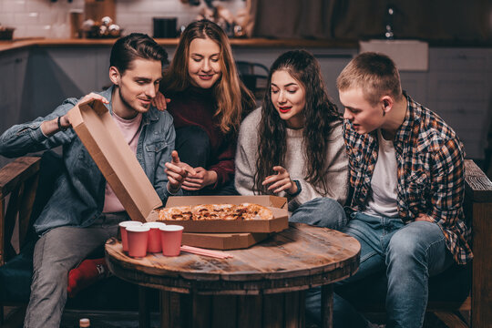 Young people choose slices of pizza at a non-alcoholic party. Young man with amputated arms celebrates birthday with friends