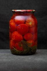 Glass jar with canned tomatoes on the table