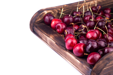 Sweet and ripe red cherry in wooden box on white background. close up image.