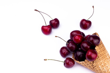 Fresh red cherries in waffle cone. Ice cream cone with ripe sweet cherry on white background with copy space. Summer creative concept flat lay. Top view.