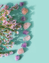 amethyst and rose quartz gemstones, flowers on green background. Healing stones for Crystal Ritual, esoteric spiritual practice, spa, relax. modern magic. reiki healing therapy, life balance concept