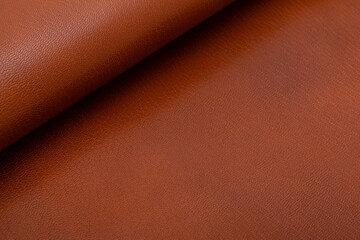 Brown glossy folded natural cow leather on the wooden table	
