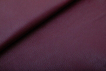 Dark burgundy folded natural premium cow leather on the wooden table	
