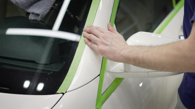 Car wrapping with adhesive tape, car detailing. Installation of polymer protection for the paintwork of the car body. A man puts vinyl tape on a car.