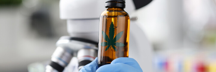 Female scientist in laboratory testing cbd oil extracted from marijuana plant closeup