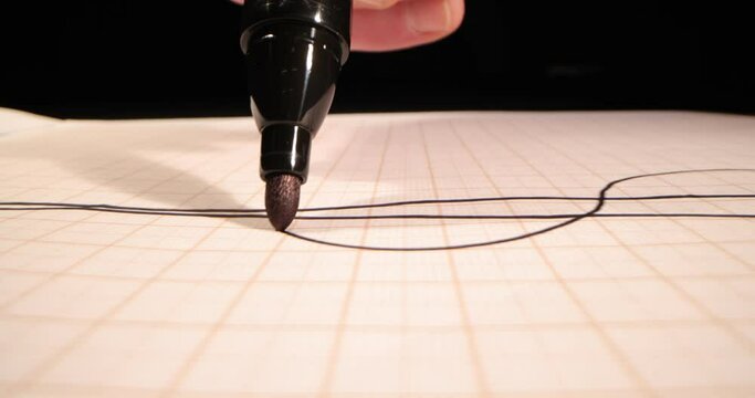 A close-up felt-tip pen drawing black sinuous lines. Artist hand drawing a flat line with a felt-tip pen on white paper macro,side-view camera tracking. 4k