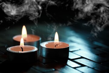 Candles over dark background. Used, almost extinguished. Burned out. Mystical smoke swirls in the dark