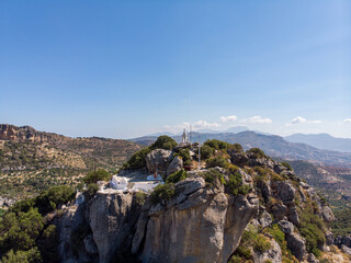 Timios Stavros Kirche auf Kreta, Griechenland, gebaut auf dem Gipfel eines kleinen Berges mit Gipfelkreuz und der Griechland Flagge