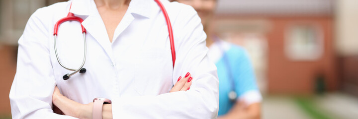 Doctors veterinarians stand confidently with folded hands on background of farm