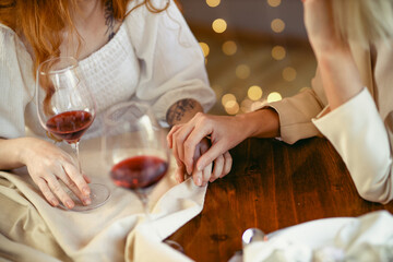 lesbian couple having dinner in a restaurant. Close-up of hands of a loving couple