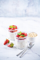 Oatmeal porridge with milk and fresh strawberries in a glass