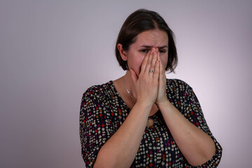 woman frowns face in discontent, cries from pain, wears casual, models over white studio wall. People, depression, negative