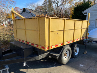 Yellow dumpster on a black trailer in a homes driveway