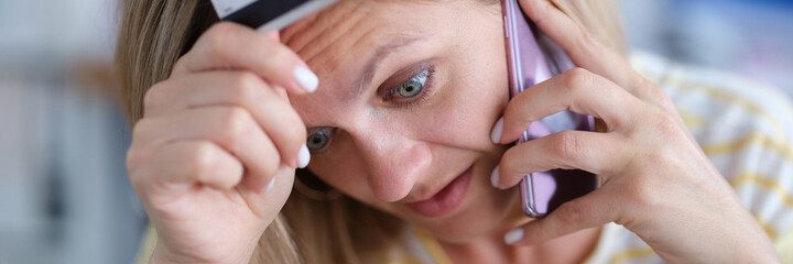 Upset woman in stress holds bank card and talks on phone
