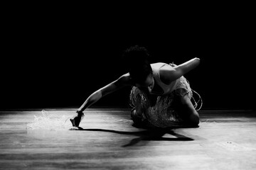 Black and white portrait of dancer crouching on stage