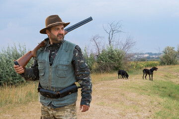 Hunter man in camouflage with a gun during the hunt in search of wild birds or game. Autumn hunting...