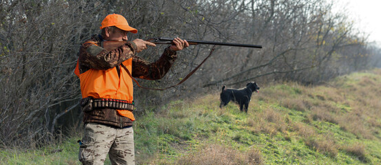 Hunter man in camouflage with a gun during the hunt in search of wild birds or game. Autumn hunting season.