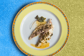 Overhead view of a presentation on a decorated plate of cooked baked sea bream with sauce on an...