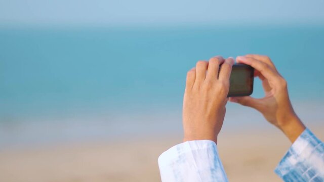 Close up shot of girl photographer shooting video with action camera at beautiful island beach. Young female vlogger, Social media influencer on location in Asia.
