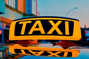 Lit taxi sign on roof of taxi car in the city