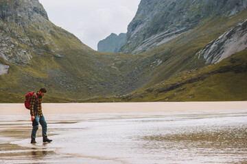 Fototapeta premium Man hiking solo in Norway travel adventure vacations outdoor active healthy lifestyle tourist backpacking on sandy Horseid beach Lofoten islands