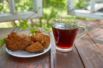 cup of tea with chaga and a dried chaga mushroom lies next to it on a plate