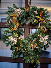 Stylish christmas wreath made of mimosa, bows and decorative wood