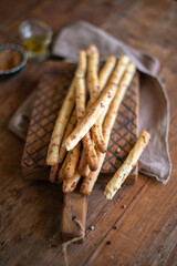 Italian grissini bread sticks with dried herbs on a wooden background.