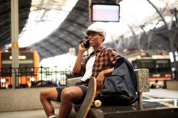 Fototapeta premium Happy young man waiting for the train. African man waiting in a subway. Man using a phone