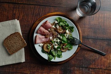 Lamb's lettuce with ham and shiitake mushrooms, on rustic tabletop. View from above.